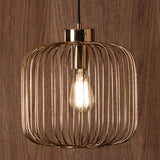 A gold-finished pendant light with vertical slats encasing an illuminated bulb, suspended against a wood-grain background.