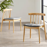 Two wooden chairs with grey cushions are positioned on a light wood-patterned floor, near a window with a green plant to the side.