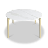 A round table with a white marble top and gold-colored legs stands stationary against a plain white background.