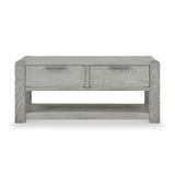 A wooden coffee table with two drawers and a lower shelf, featuring a light gray wood grain finish, presented against a white background.