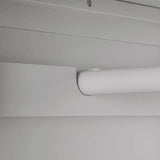 A cylindrical object, possibly a blind or a shade, is rolled up near the ceiling; it suggests an interior setting. No actions or text are present.