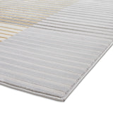 A textured rug with alternating white and gold diagonal stripes on one half and solid gray on the other, laid on a flat surface.