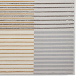 A carpet with contrasting striped patterns, transitioning from multicolored to grayscale.