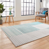 A modern rug with green and turquoise stripes lies on a wooden floor, flanked by minimalist furniture and large windows with a city view.