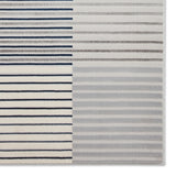 A striped rug with varying patterns and shades of grey and blue against a white background. The texture appears soft and plush.