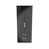 A black wardrobe with two doors and a drawer at the bottom, featuring silver handles, stands against a plain white background.