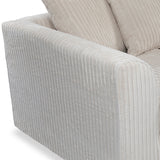 A corduroy-textured, beige armchair corner, with visibly plush cushions and ridged fabric.