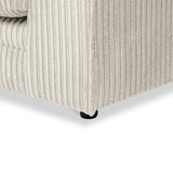 Cream-colored, corduroy-textured couch corner with a single black foot visible, set against a plain background.