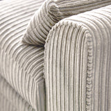 A close-up of a grey, corduroy upholstered couch corner, showing the texture and folds of the fabric in detail.