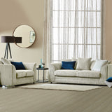 Striped sofa and armchair with blue and white cushions, a floor lamp, and round mirror, in a neutral-toned living room with sheer curtained window and wooden floor.