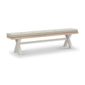 A long wooden bench with a padded seat rests idle, supported by white X-shaped legs, against a neutral background.