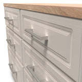 A wooden countertop rests on a gray cabinet with several closed drawers, featuring metallic handles, against a blank background.