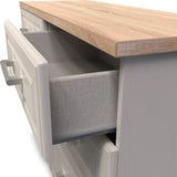 A grey upholstered built-in bench is partially pulled out from beneath a wooden kitchen countertop, suggesting a space-saving seating solution.