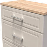 A close-up of a white chest of drawers with a light wood countertop and sleek, horizontal silver handles.