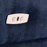 A metallic clothing tag with two holes and a slot is attached to a textured blue fabric, suggesting a garment detail.