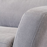 Close-up of a grey fabric sofa showcasing texture, with focus on the armrest and cushion in a home interior setting. No text present.