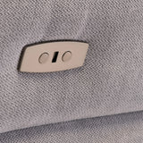 A beige recliner lever on a textured gray fabric. The lever appears flush against the upholstery, suggesting an adjustable furniture feature.