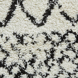 A close-up of a textured rug with a black and white geometric pattern, primarily featuring diamond shapes and zigzag lines.