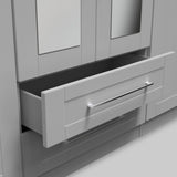 A partial view of a white cabinet with one drawer partially open, revealing its dark interior, set against a light grey background.