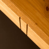 Wooden dovetail joints protrude from a panel, demonstrating craftsmanship against a dark background.