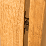 Metal hinge connecting two wooden panels, partially concealed between them, suggesting a door or cabinet in a wooden structure.