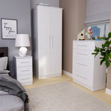 White furniture including a wardrobe, chest of drawers, and bedside table, arranged in a bedroom with a framed picture reading "our happy place."