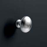 A silver doorknob protrudes from a dark grey surface, casting a soft shadow to the right. There is a minimalistic and clean aesthetic.