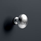 A spherical silver doorknob affixed on a dark gray surface, casting a soft shadow, with a minimalist and modern aesthetic.