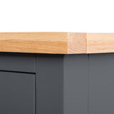 A wooden surface with a sanded corner rests atop a dark cabinet against a grey background.