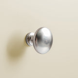 A round, silver-colored doorknob is mounted on a light beige surface, seemingly a door, with no visible action occurring.