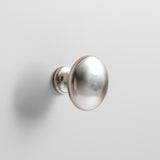 A spherical silver doorknob is mounted on a white surface, reflecting light with a soft shadow behind it.