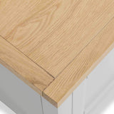 A light wooden tabletop with a visible corner, showcasing its grain and texture, over a blurred white background.