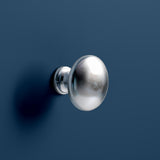 A shiny silver doorknob is mounted on a dark blue surface, casting a soft shadow to the right.