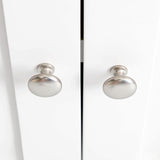 Two round, silver-colored knobs are attached to a pair of closed, white cabinet doors, reflecting light in a bright interior.