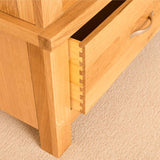 A wooden cabinet drawer partially open, revealing dovetail joint construction, against a beige textured carpet background.