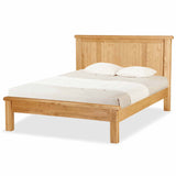 A wooden bed with a white mattress and two pillows against a white background.