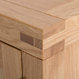 A close-up of wooden planks with visible grain, dovetail joint connecting two pieces, in a well-lit setting.