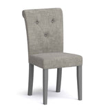 A grey upholstered dining chair with button tufting on the backrest, set against a white background.