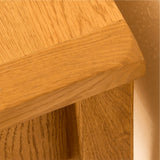 A close-up of a wooden corner, highlighting the grain and texture, likely part of furniture against a beige background.