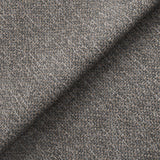 Textured fabric with a herringbone pattern is folded, showing depth and the weave's intricate detail. The context is a close-up, showing the fabric's quality.