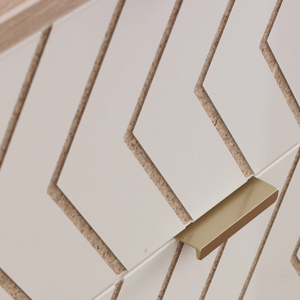 White parallelogram tiles with tan edges are mounted on a wall, creating a geometric pattern; a gold-colored fixture protrudes from beneath.