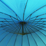 A blue umbrella opened against a backdrop, showcasing its intricate black skeletal structure radiating from the central hub.