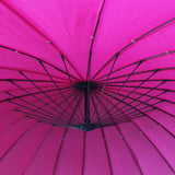 A vibrant pink umbrella is open, revealing its black structural framework against a bright fabric background.