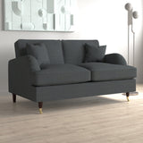 A dark grey sofa with two cushions rests idly in a simple room with a geometric wall art piece and a modern floor lamp.