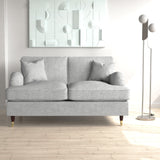 A grey two-seat sofa with cushions sits in a room, accompanied by a floor lamp to the right and geometric wall art above, all in a cleanly designed interior space.