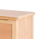 A wooden table corner against a white background, showing the tabletop and leg connection with visible wood grain and a subtle shadow.