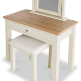 A wooden vanity table with a matching stool and a hinged mirror, set against a white background. The table features a single drawer with a silver knob.