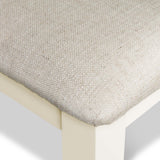 A close-up of a textured cushion resting on a beige surface, evoking a sense of softness and comfort in a minimalist setting. No text is present.