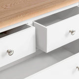 White wooden drawers partially open revealing empty interiors, with metal round knobs, against a neutral background.