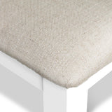 A close-up of a beige fabric cushion resting on a white surface, detailing its texture.